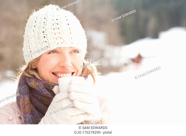Woman drinking coffee outdoors in snow