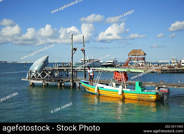 Local man on a traditional boat used for daily trips at North Beach-Playa Norte in front of the typical houses near the town center, Isla Mujeres, Cancun