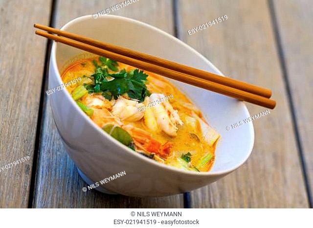 Schale Teller mit frisch zubereiteter Tom Yam Suppe mit Languste und Koriander