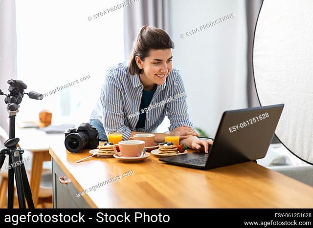 female food photographer with laptop in kitchen