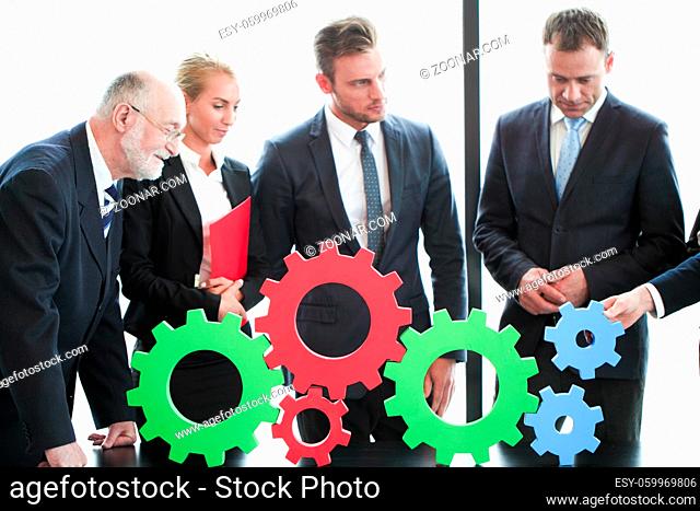 Business people assembling cogwheels, teamwork concept