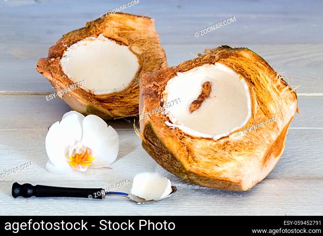 Kokosnuss mit Löffel und Orchidee auf Holztisch