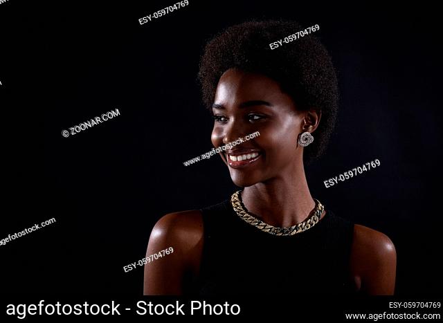 Portrait of young smiling black woman. Beautiful curly haired african american girl wear black dress with golden jewelry