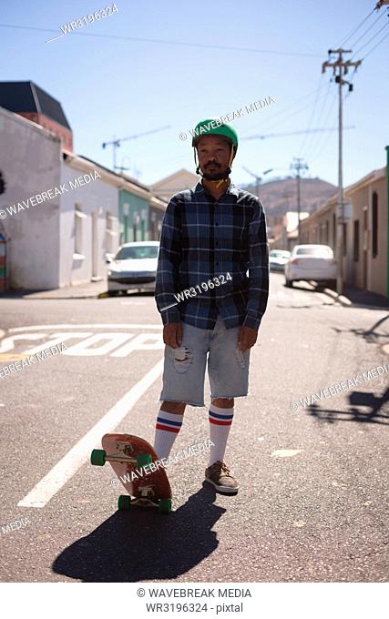 Man standing with skateboard in street