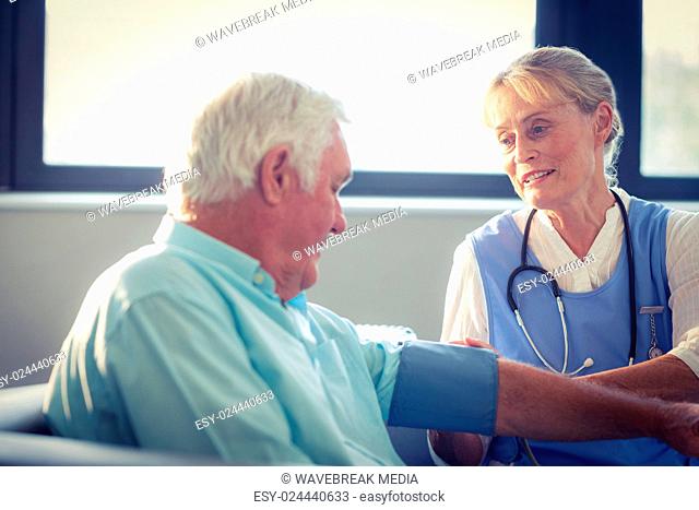 Female doctor checking blood pressure of senior man