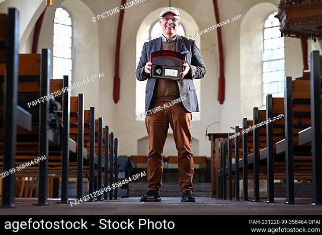 FILED - 14 November 2023, Lower Saxony, Leer: Pastor Ingo Brockmann holds the digital bell bag in the collection bowl version