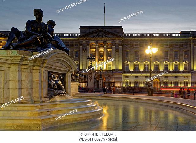 UK, London, lighted Buckingham Palace at dusk with fountain in the foreground