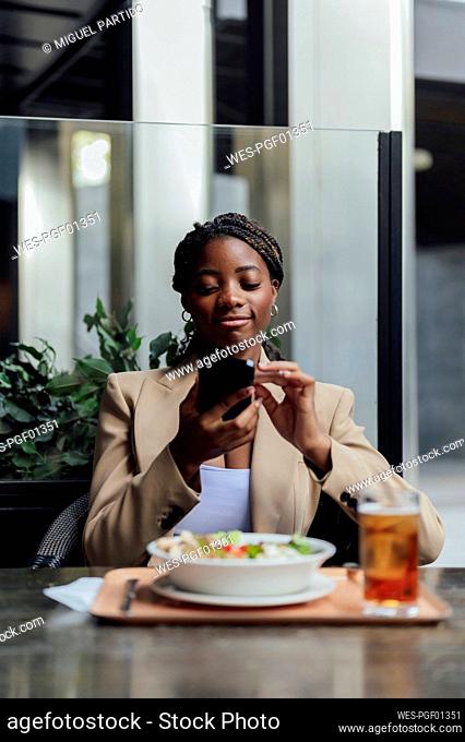 Smiling businesswoman surfing net sitting at cafe
