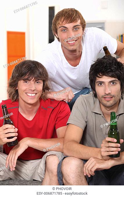 three 18 years old boys drinking beer at home