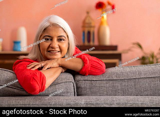 Portrait of an old woman leaning on sofa and looking at camera
