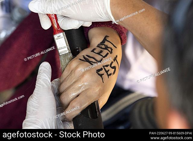 dpatop - 27 June 2022, Berlin: A police officer detaches the sticker of a taped actist in front of an entrance of the Ministry of Finance
