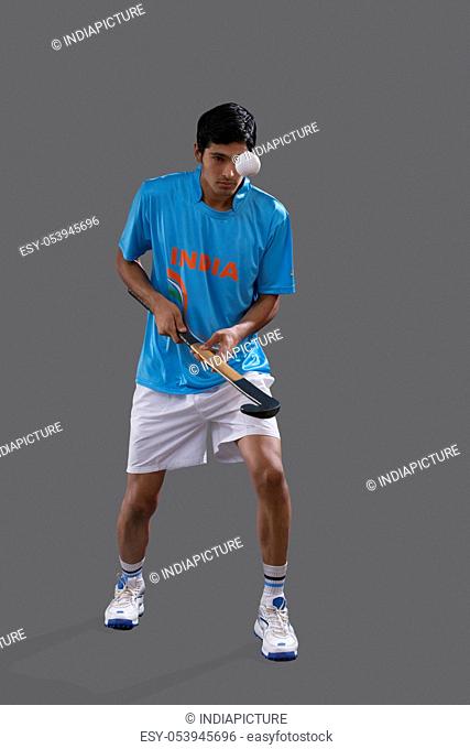 An Indian sportsman practicing hockey isolated over gray background