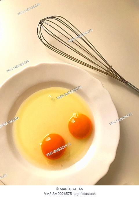Two eggs in a dish and beater