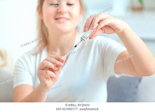 Portrait of young woman filling syringe from ampule
