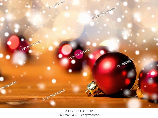 christmas, decoration, holidays concept - close up of red shiny balls on wood over golden lights background