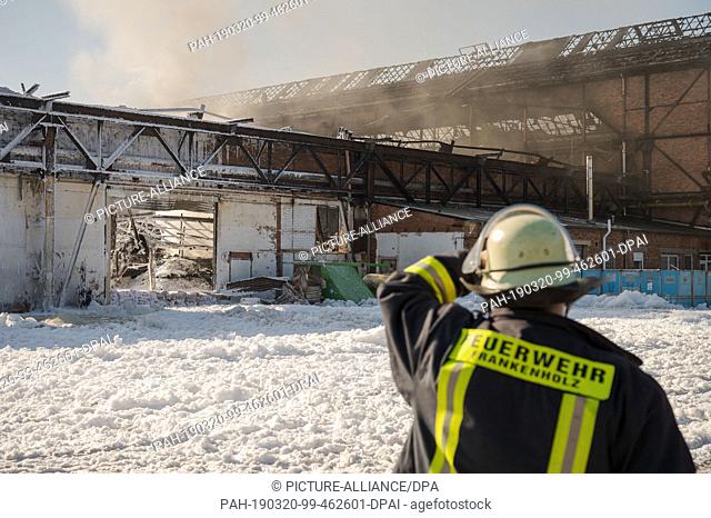 20 March 2019, Saarland, Homburg: Firefighters extinguish last sources of fire after a fire in a warehouse of a plastics manufacturer