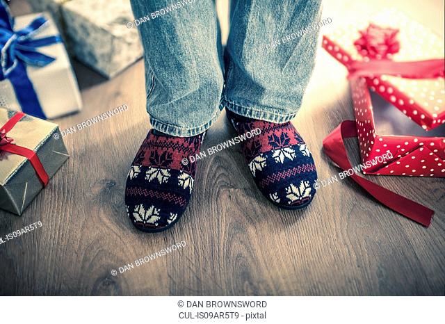 Man wearing slippers with christmas gifts on floor