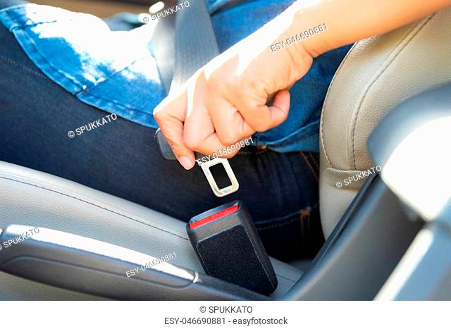 Closeup woman hand sitting inside car fastening seat belt. Safety belt safety first