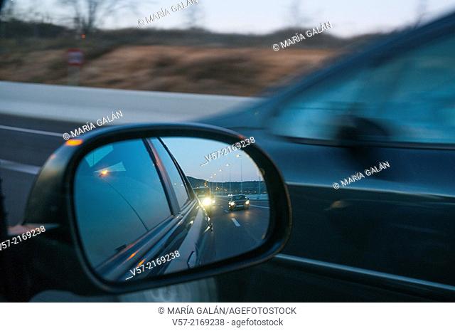 Freeway viewed on a rear mirror at nightfall