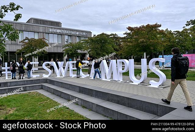 04 October 2021, Berlin: Students walk across the grounds of Freie Universität Berlin in front of the lettering ""#yeswecampus""