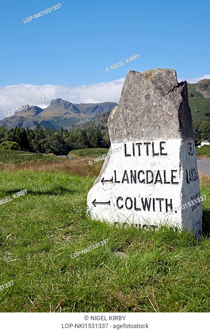 England, Cumbria, Elterwater. Stone road sign near Elterwater with Langdale Pikes in the background