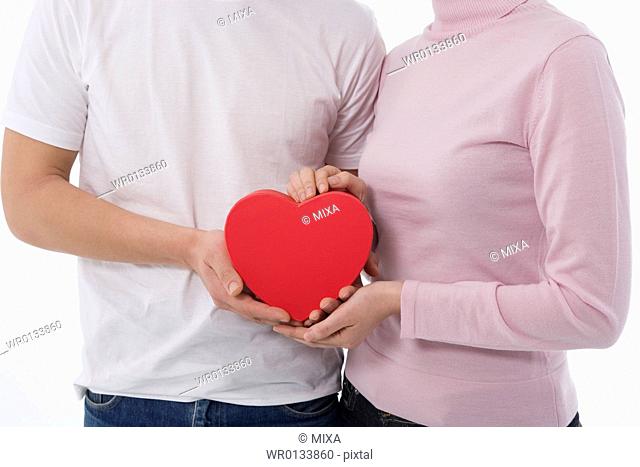 Man and woman holding heart-shaped box