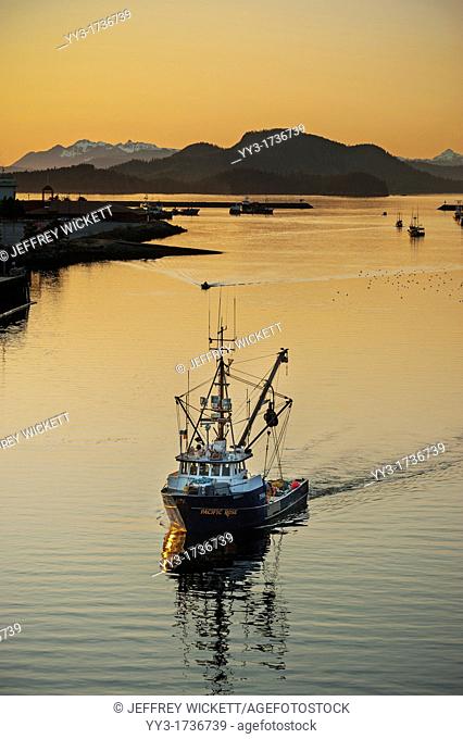 Commercial fishing vessel sailing through channel in Sitka, Alaska, USA