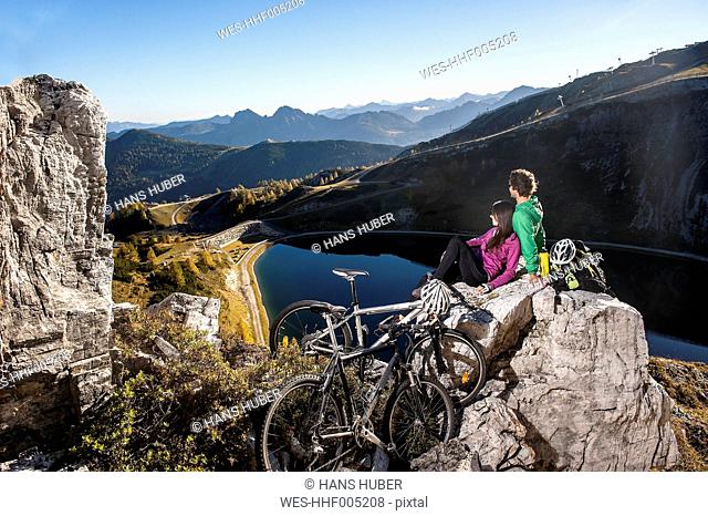Austria, Altenmarkt-Zauchensee, young couple with mountain bikes in the mountains