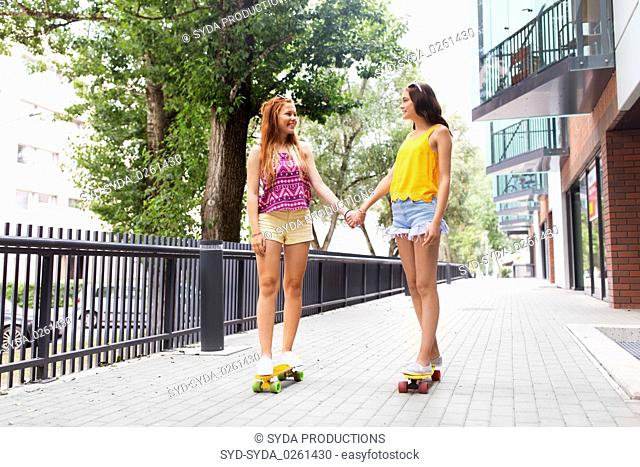 teenage girls riding skateboards in city