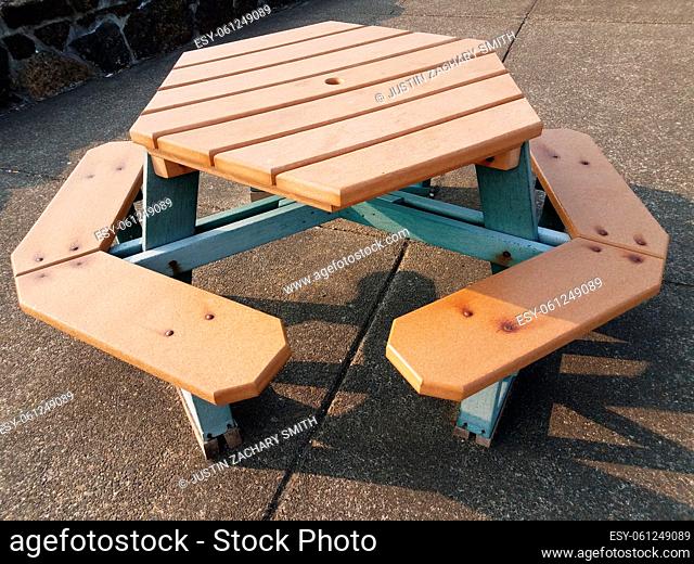 brown wood hexagon picnic table on cement or pavement