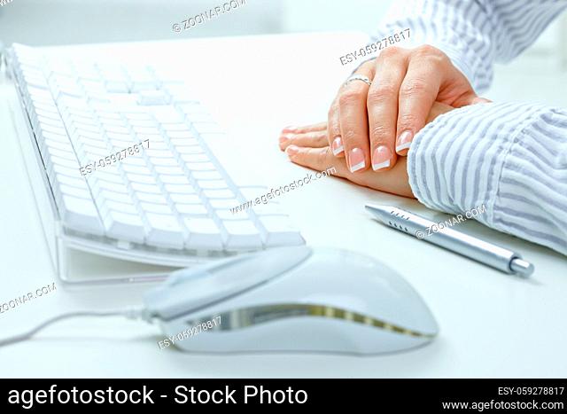 Closeup picture of female hands on desk, beside computer keyboard, mouse and pen