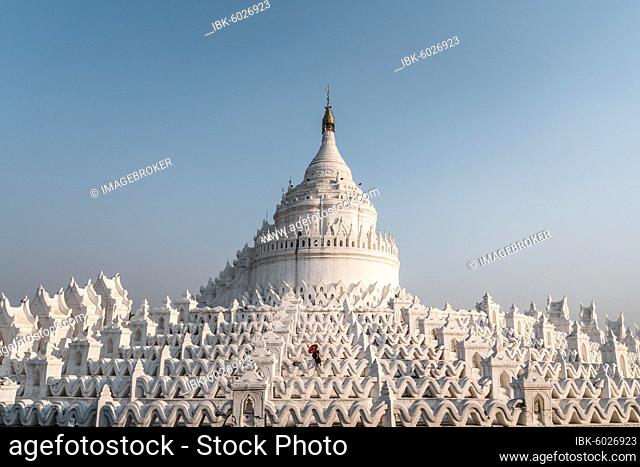 Buddhist monk stands with red umbrella in front of Hsinbyume Pagoda, Mingun, Myanmar, Asia