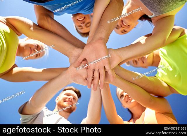group of happy sporty friends stacking hands