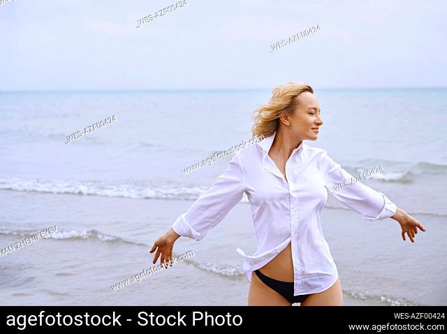 Woman standing with arms outstretched at sea