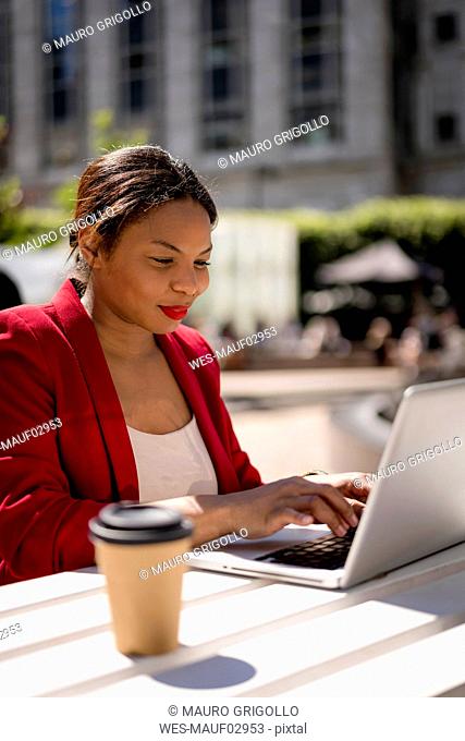 Portrait of smiling businesswoman working on laptop outdoors, London, UK