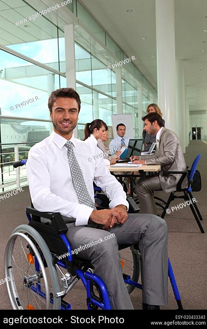 Businessman in wheelchair with colleagues in background