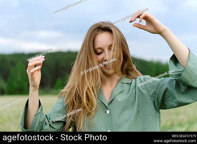 Playful young woman with long blond hair on field