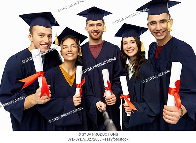 happy graduates with diplomas taking selfie
