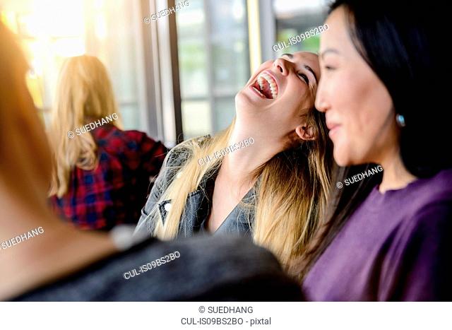 Female student friends laughing and chatting in university