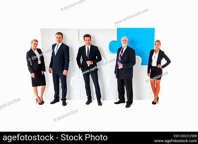 Business teamwork and cooperation concept . Portrait of group of business people with giant puzzle pieces . Partnership and collaborationconcept