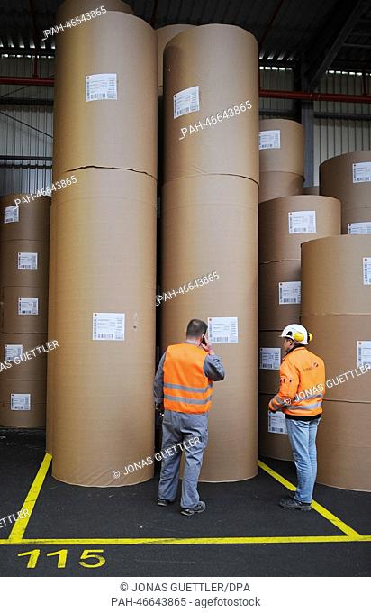 Two workers stand in front of packaged paper rolls at the logistics hall of company Stora Enso in Hagen, Germany, 20 February 2014