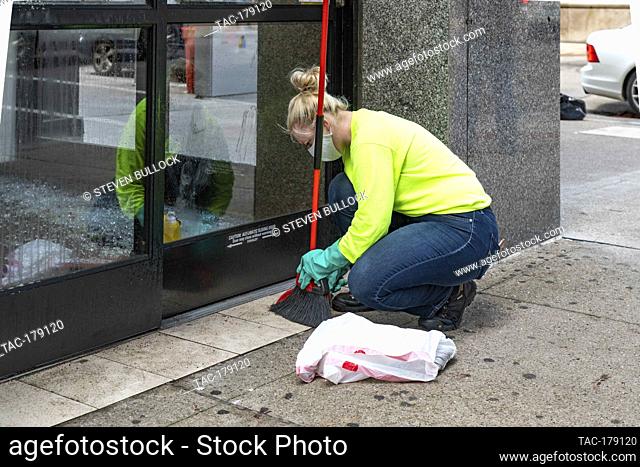 A worker cleans up broken glass at the doorway of CVS Pharmacy at 4th St and Chestnut on May 30, 2020 in Louisville, Kentucky