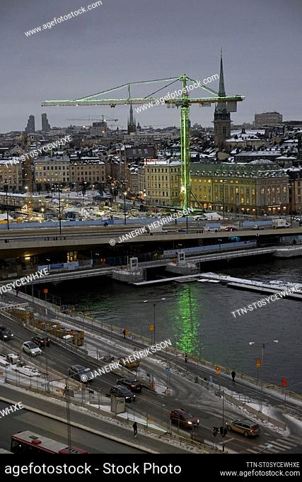 Apicture taken on Dec. 14, 2023, shows a construction crane illuminated in green with the Stockholm skyline in the background