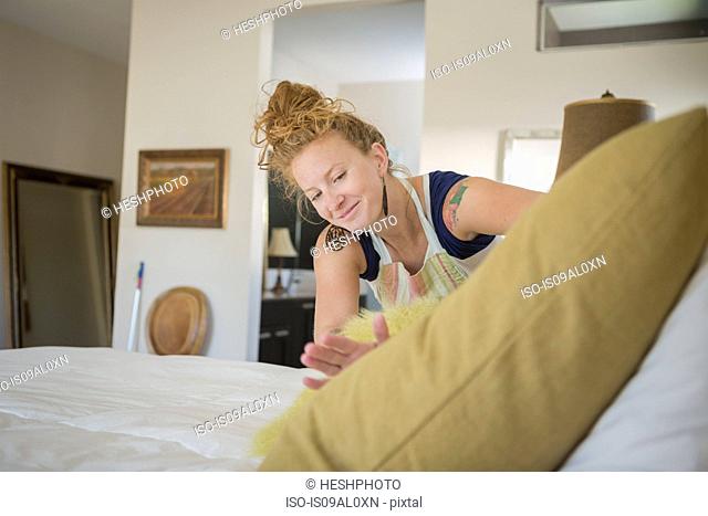 Young woman cleaning bedroom with green cleaning products