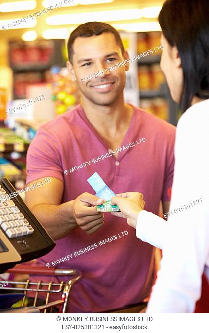 Customer Using Vouchers At Supermarket Checkout
