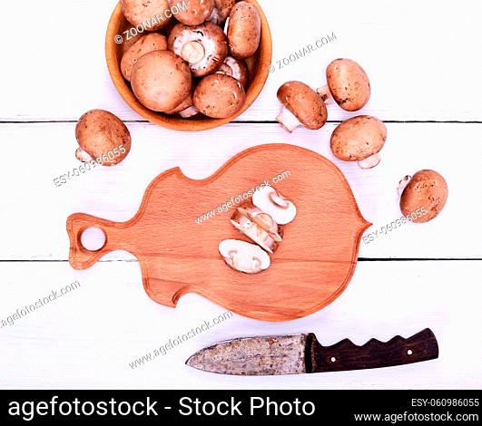Fresh mushrooms champignons on a wooden cutting board, top view