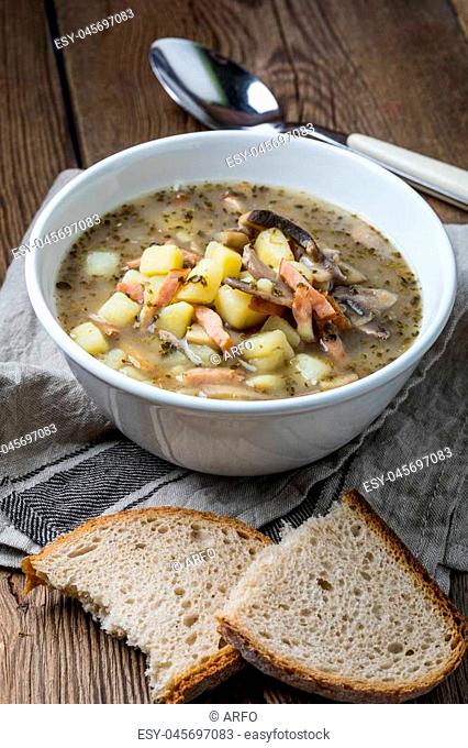 Sour rye soup with potatoes, mushrooms and smoked meat