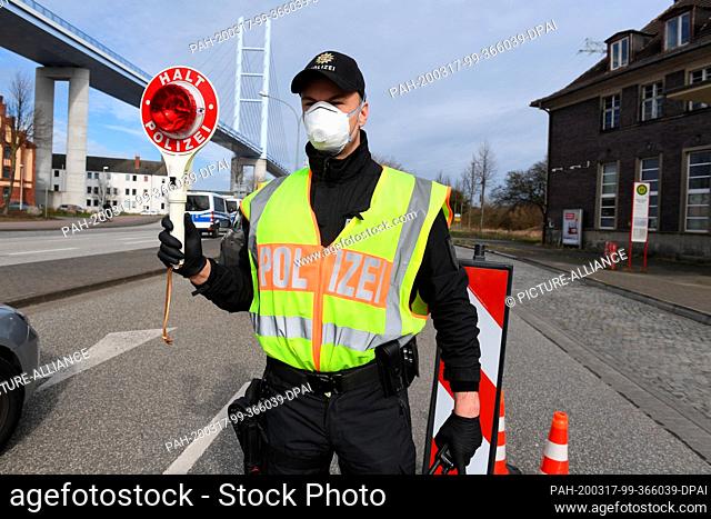 17 March 2020, Mecklenburg-Western Pomerania, Stralsund: With a holding trowel, a police officer regulates the vehicle traffic in the direction of the island of...