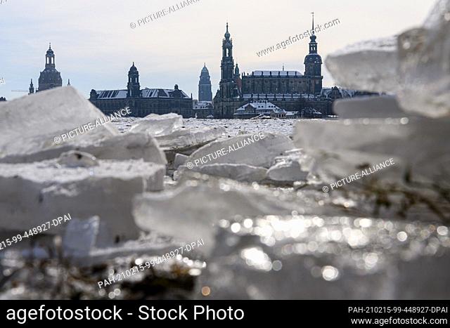 15 February 2021, Saxony, Dresden: Ice lies at low temperatures on the frozen Elbe meadows in front of the Old Town with the Frauenkirche (l-r), the Ständehaus