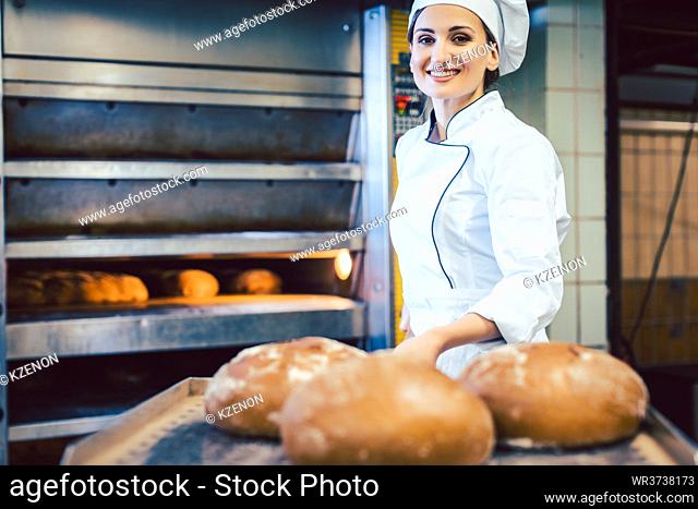 Baker woman showing freshly baked bread on shovel, one can almost sniff the freshness